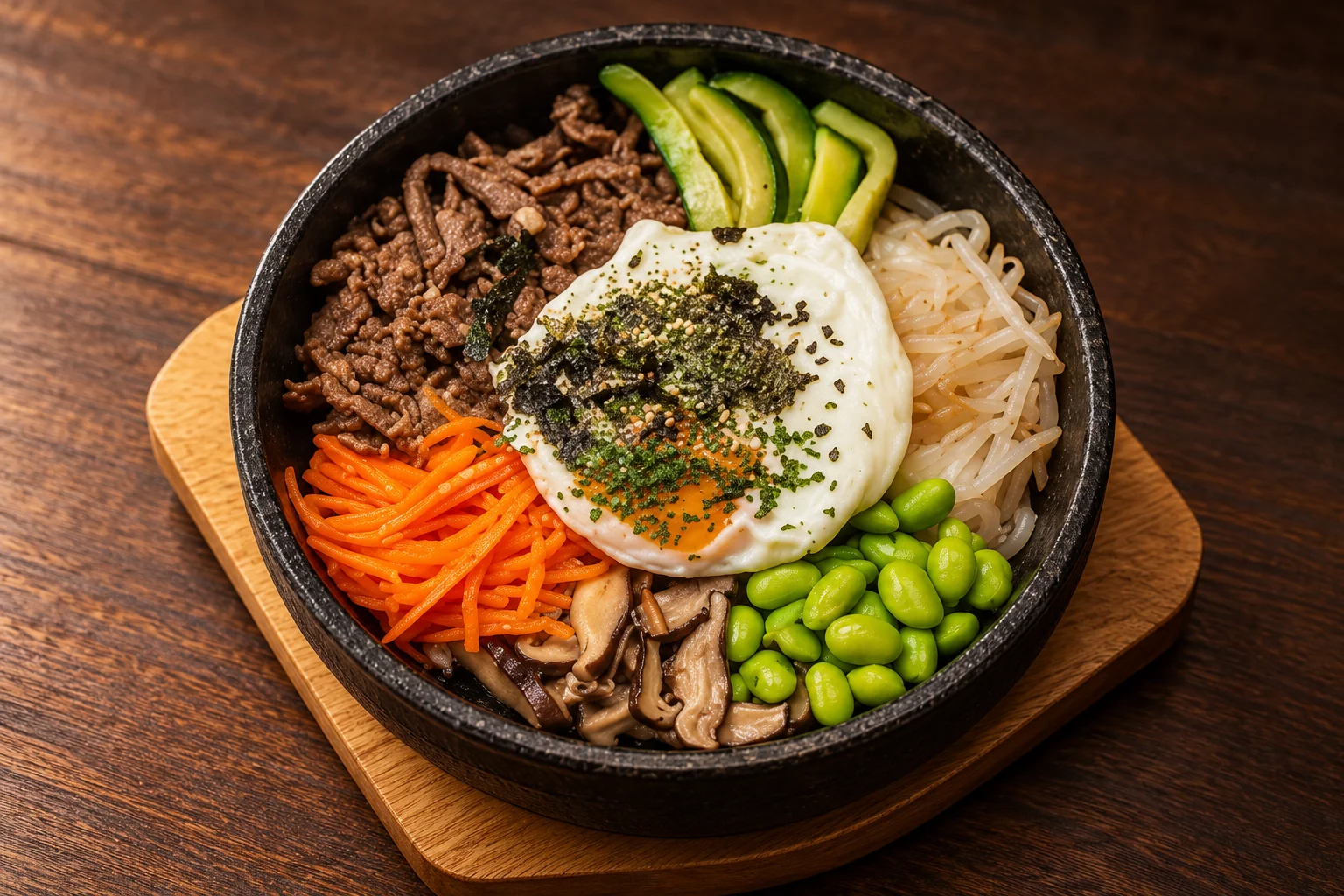 Bibimbap dans un bol noir sur une table en bois